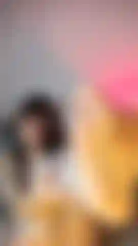 Uma gata de lingerie branca e meia arrastão, acariciando seus pés e sorrindo alegremente para a câmera.