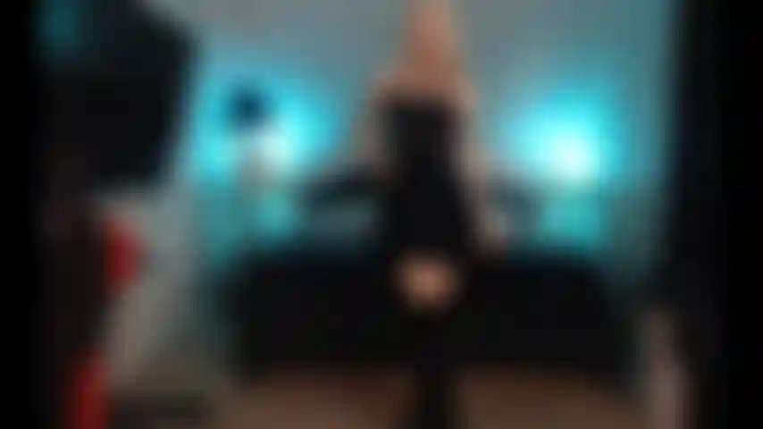 Cumming, usando vestido preto e botas.