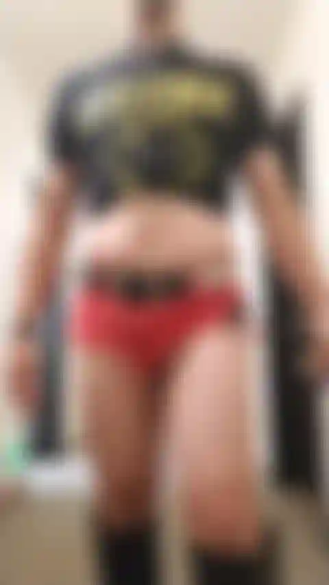 Crossdresser posando sexy no corredor do hotel vestindo shorts jeans e botas.